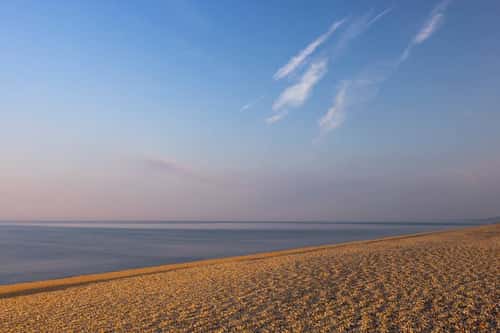 Landscape view of Chesil Beach at sunrise, Weymouth, Dorset, UK, June 2023