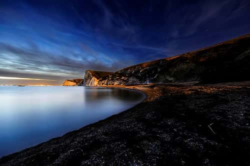 View of cliffs along Jurassic Coast at night after sunset with stars visible, Dorset, England, UK, November
