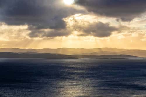 View across Sound of Jura towards Knapdale with heavy clouds and sunbeams, Jura, Scotland, UK, October